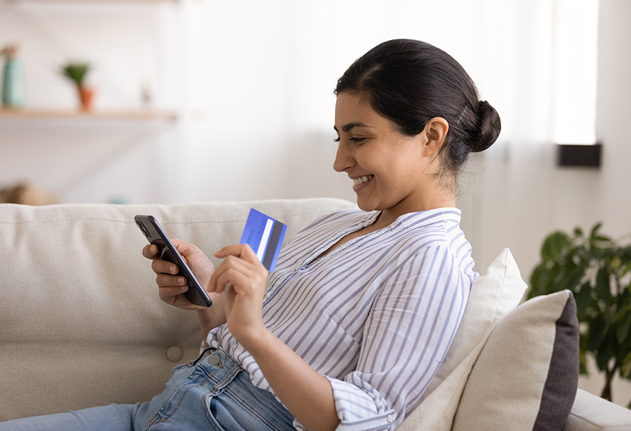 femme regardant sa carte bancaire et son téléphone portable