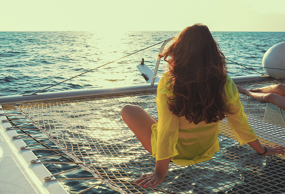 femme assise de dos sur un bateau regardant la mer