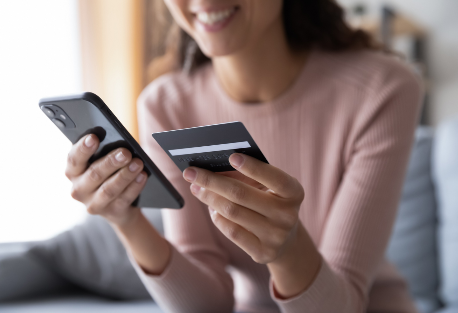 Femme tenant un téléphone et une carte bancaire