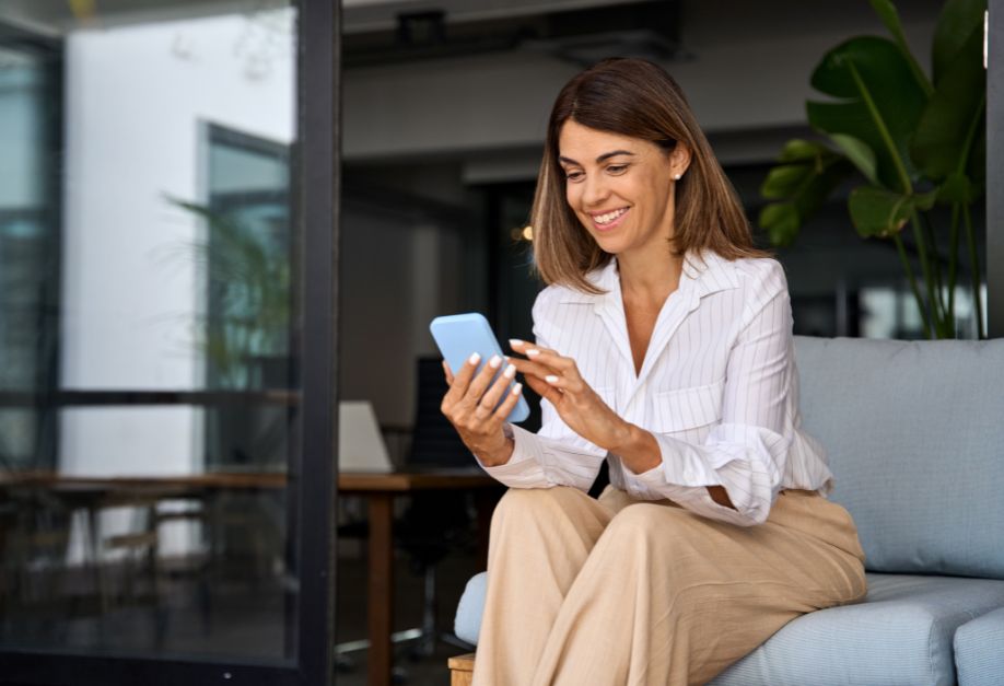 Chic, happy woman sitting looking at her phone