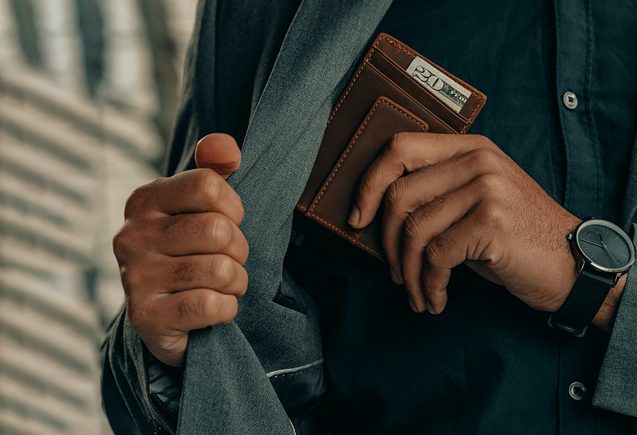 man putting his leather wallet into his suit pocket