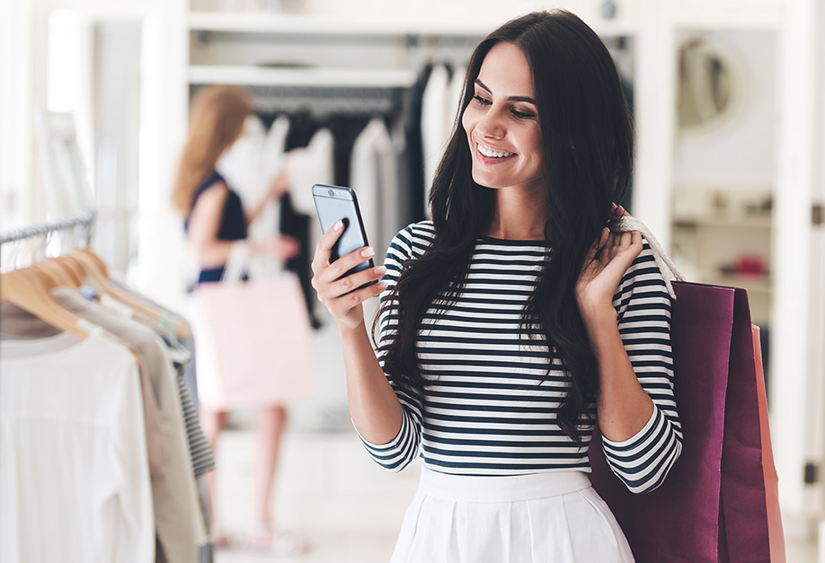 happy woman looking at her smartphone while shopping