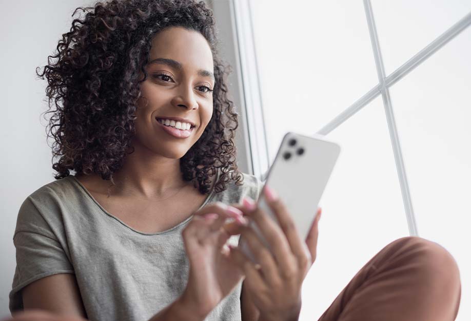 femme souriante avec son smartphone à la main