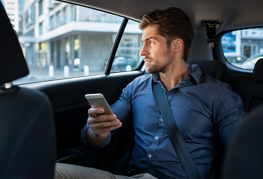 man sitting in the back of a car with a smartphone in his hands
