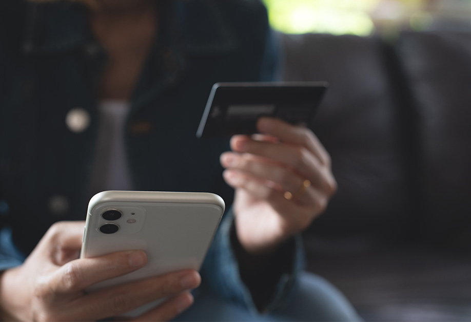 woman looking at her bank card and smartphone