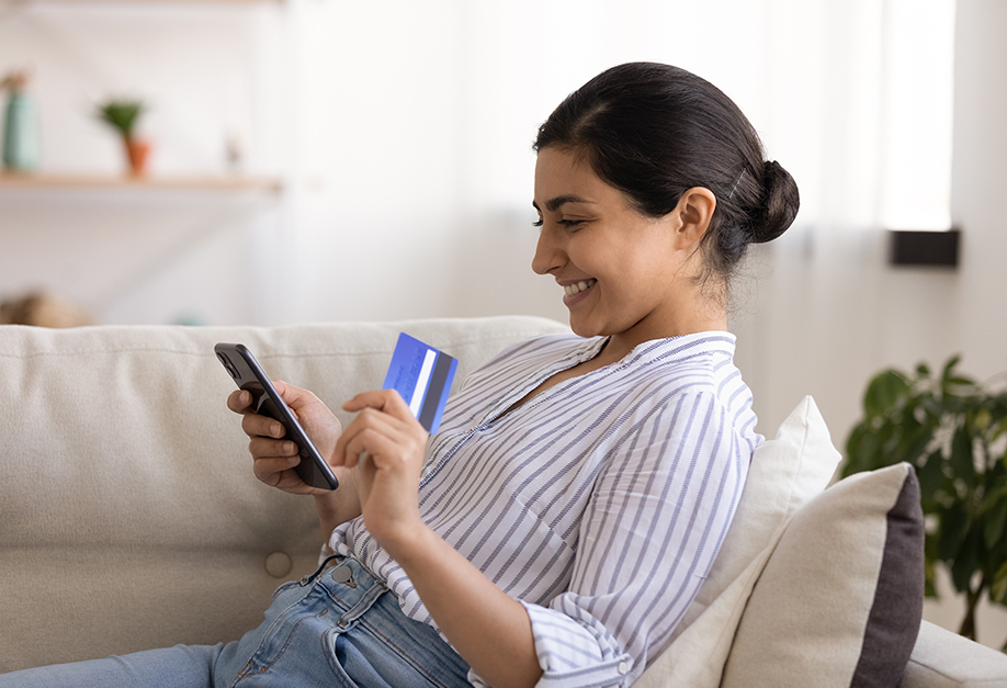femme regardant sa carte bancaire et son smartphone